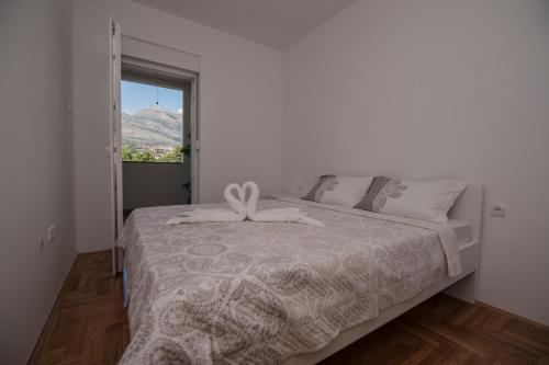 a white bedroom with a bed with a window at Cozy Apartment SINN in Trebinje