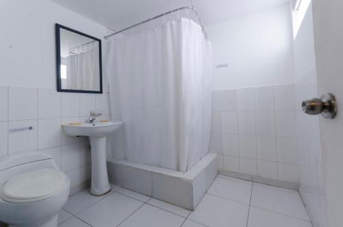 a white bathroom with a toilet and a sink at Jose Luis Hostal Boutique in Lima