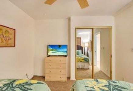 a bedroom with a bed and a dresser with a television at KOA Resort 5D in Kihei