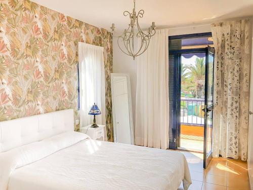 1 dormitorio con cama blanca y lámpara de araña en Sea View Meloneras Terrace Duplex +Wifi +Barbecue, en Meloneras
