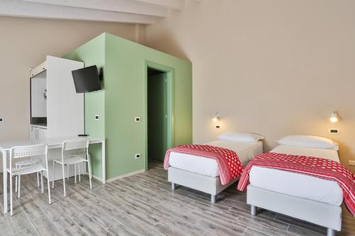 フィオレンツオーラ・ダルダにあるアグリツーリズモ バッティブエのテーブルとデスクが備わる客室内のベッド2台