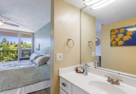a bathroom with a sink and a bed with a mirror at Maui Banyan G203a in Wailea