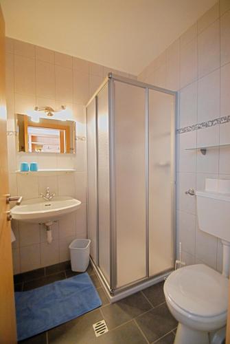 a bathroom with a shower and a toilet and a sink at Gästehaus Sonja in Niederau