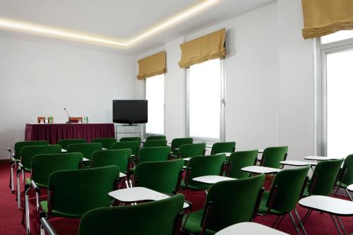 a room with green chairs and tables and a tv at Best Western Park Hotel Continental in San Donà di Piave