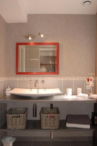 La salle de bains est pourvue d'un lavabo, d'un miroir et de paniers. dans l'établissement La Chaiserie, à La Croix-Saint-Leufroy