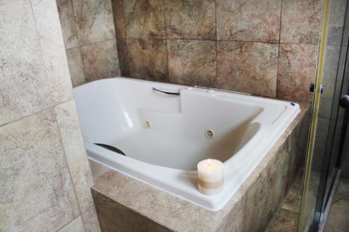 a bathroom with a bath tub with a candle in it at Hotel Boutique La Rioja in Atlixco