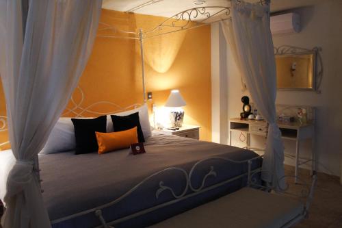 a bedroom with a canopy bed with an orange pillow at Hotel Boutique La Rioja in Atlixco