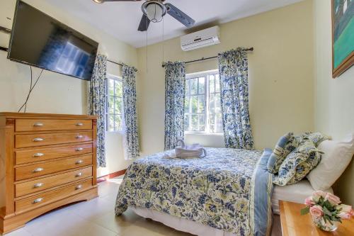 a bedroom with a bed and a tv and windows at Casa de Cahal Pech in San Ignacio