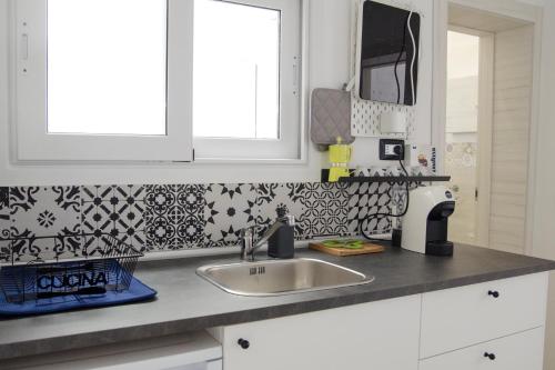 uma cozinha com um lavatório e azulejos pretos e brancos em Donna Nunzia Home em Noto