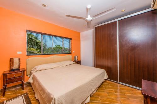 - une chambre avec des murs orange, un lit et une fenêtre dans l'établissement La Cometa 15, à Tamarindo