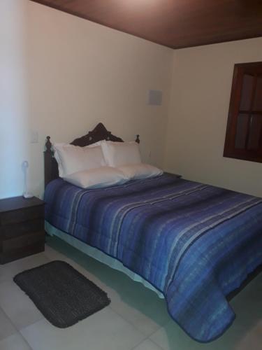 a bedroom with a bed with a blue comforter at Chales netuno in Monte Verde