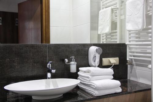 a bathroom with a white sink and a pile of towels at Apart Neptun in Gdańsk