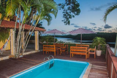 a swimming pool with chairs and a table and umbrellas at Pousada Canto do Rio in Prado