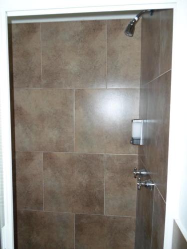 a bathroom with a shower with a large tile wall at Hotel Montroi City in Colima