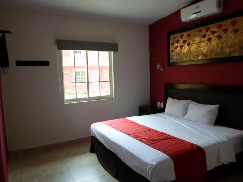 a bedroom with a bed with a red wall at Hotel Montroi City in Colima
