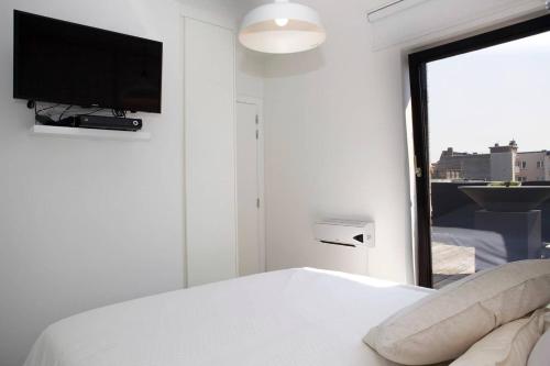 ein Schlafzimmer mit einem Bett und einem TV an der Wand in der Unterkunft Modern appartement centrum Oostende met enorm dakterras (parking beschikbaar) in Ostende