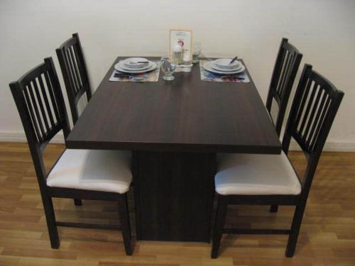 una mesa de madera con 4 sillas y una mesa negra con platos en Córdoba Suites Recoleta en Buenos Aires