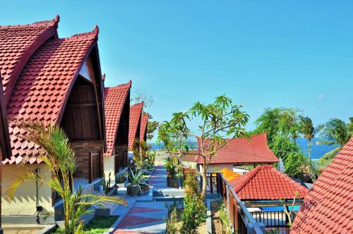 a row of houses with red roofs and trees at Surya Chandra Beach Bungalow in Nusa Penida