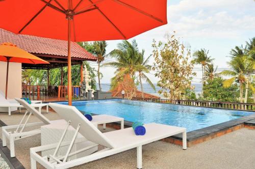 a swimming pool with two chairs and an umbrella at Surya Chandra Beach Bungalow in Nusa Penida