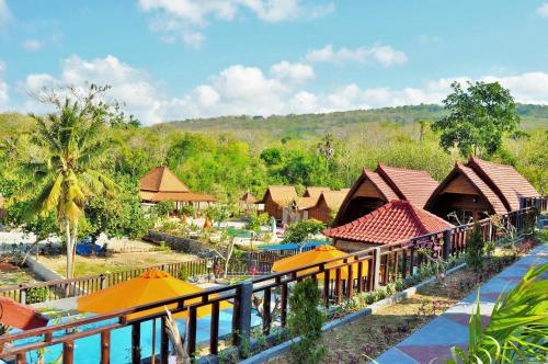 a resort with a pool and tables and umbrellas at Surya Chandra Beach Bungalow in Nusa Penida