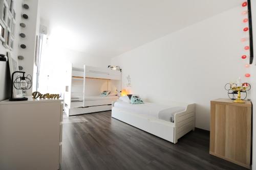 biała sypialnia z białym łóżkiem i drewnianą podłogą w obiekcie Disneyland Dream 2 - Charmant Appartement 8 pax w mieście Serris