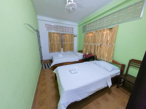 two beds in a room with green walls at Pan's Place in Vang Vieng