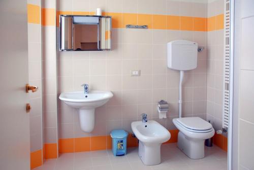 ein Badezimmer mit einem Waschbecken, einem WC und einem Spiegel in der Unterkunft Ostello La Canonica in Motta Baluffi