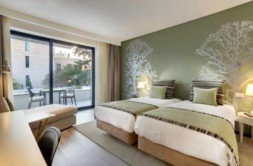 two beds in a hotel room with a balcony at Hotel Inglaterra - Charme & Boutique in Estoril