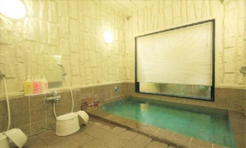 a bathroom with a swimming pool with a toilet and a window at Hotel Route-Inn Court Azumino Toyoshina Ekiminami in Azumino