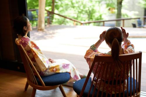 two girls sitting in rocking chairs looking out of a window at Hakone Yutowa in Hakone