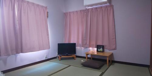 a living room with a television and a table at Guest House Fuku-chan in Kaiyo