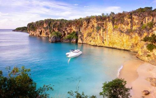 a white boat in the water next to a beach at White Sands Anguilla - Sea in Blowing Point Village