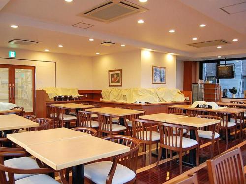 un comedor con mesas y sillas en un restaurante en Hotel Route-Inn Tsu Ekiminami -Kokudo23gou-, en Tsu