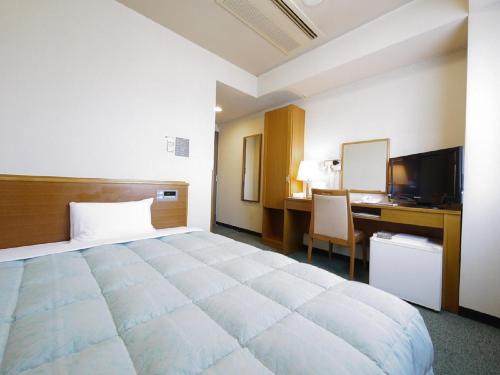 a hotel room with a large bed and a desk at Hotel Route-Inn Igaueno -Igaichinomiya Inter- in Iga