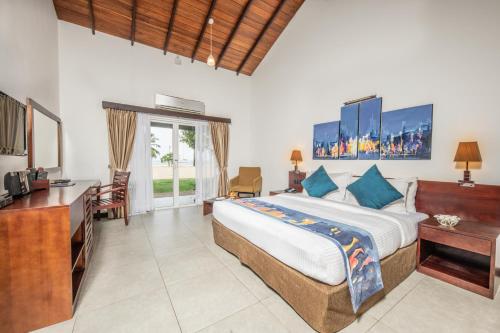 a bedroom with a bed and a desk and a television at Amethyst Resort Passikudah in Pasikuda