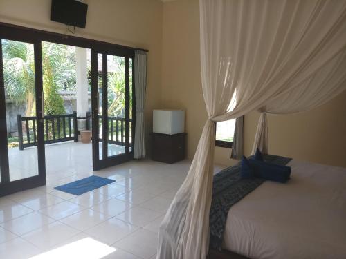 Cette chambre comprend un lit avec des rideaux et un balcon. dans l'établissement Bintang Beach Villa, à Amed