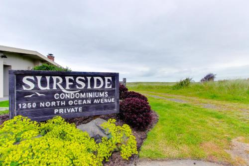 a sign for a cottage with yellow flowers next to a road at Surfside | Suite on the Sea in Gearhart