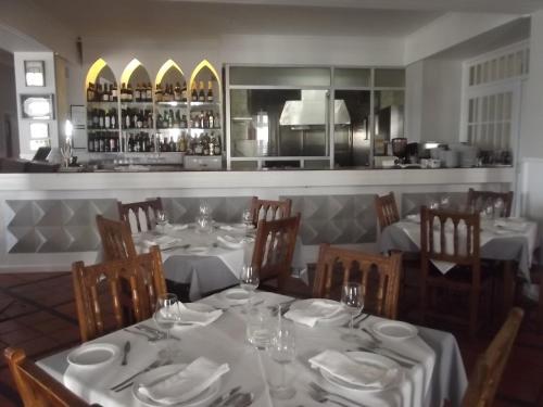 a dining room with tables and chairs with white tablecloths at Hotel Beira Mar in Angra do Heroísmo