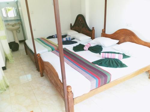 two beds in a bedroom with white sheets and pillows at Rai Family Guest in Matara