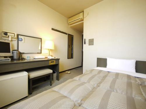 Dormitorio con cama, escritorio y TV en Hotel Route-Inn Court Kashiwazaki, en Kashiwazaki