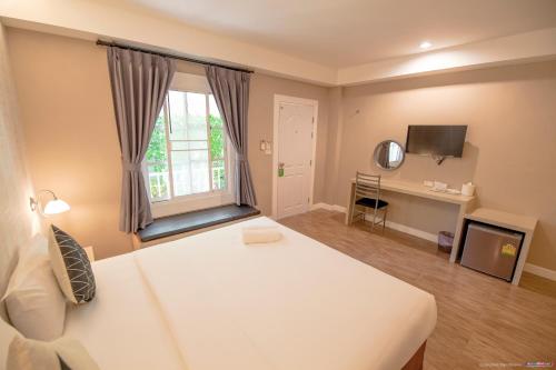 een slaapkamer met een groot wit bed en een bureau bij Color Ville Hotel SHA Certified in Sakon Nakhon