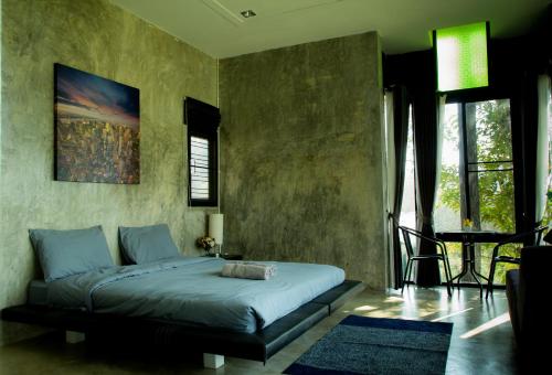 a bedroom with a bed and a table and windows at Phu Pha View Doi in Samoeng