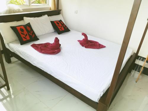a bed with two red spiders sitting on it at Rai Family Guest in Matara