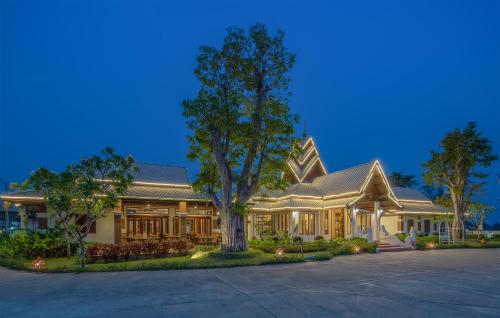 a large house with a tree in front of it at Lanna Deer Resort Chiang Mai in Chiang Mai