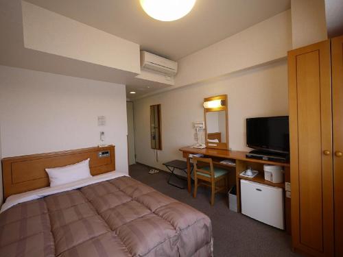 a bedroom with a bed and a desk and a television at Hotel Route-Inn Mooka in Mooka