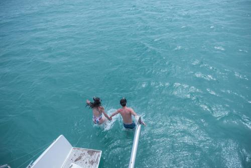 two people in the water next to a boat at Amethyst Resort Passikudah in Pasikuda