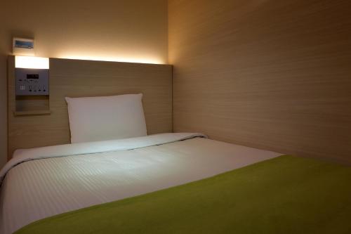 a small bedroom with a white bed in it at Keio Presso Inn Gotanda in Tokyo
