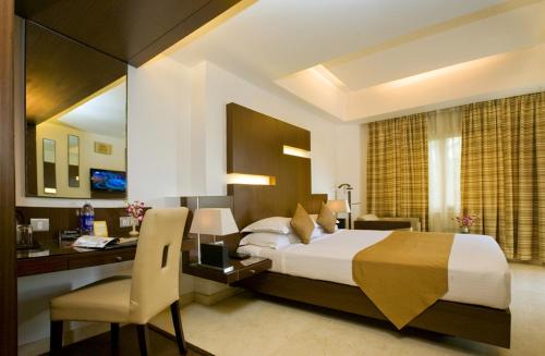 a hotel room with a bed and a desk and a desk at The President Hotel in Bangalore
