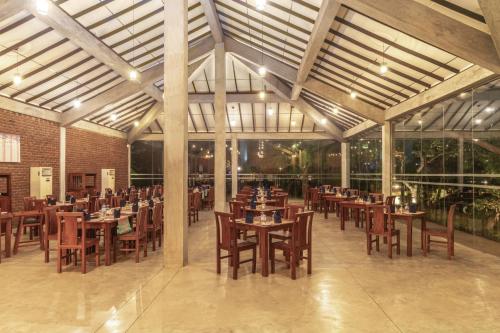a restaurant with wooden tables and chairs in a building at Amethyst Resort Passikudah in Pasikuda