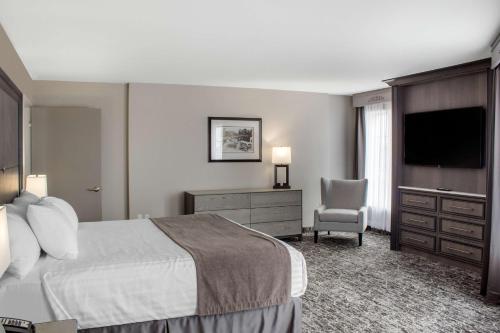 a hotel room with a bed and a television at Chateau Moncton Trademark Collection by Wyndham in Moncton